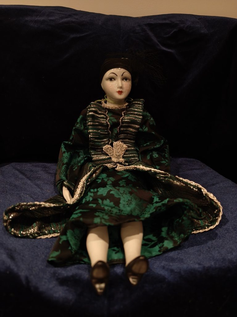 Porcelana menor 45cm — Tocado negro liso con mechón de plumas, vestido damasco ver…